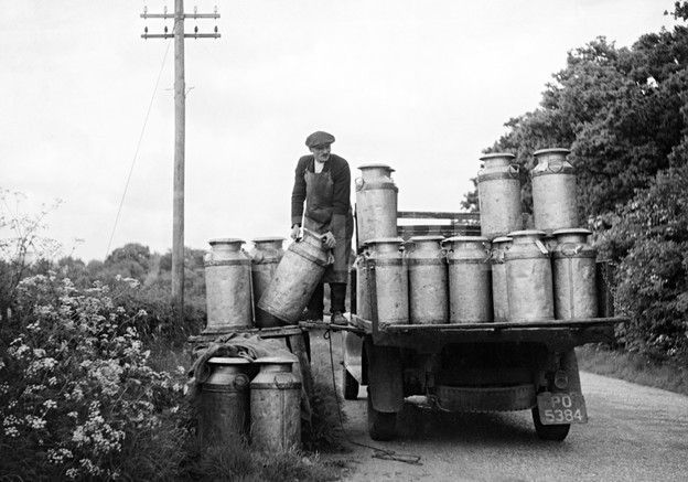 milk churns being loaded onto a lorry at a farm